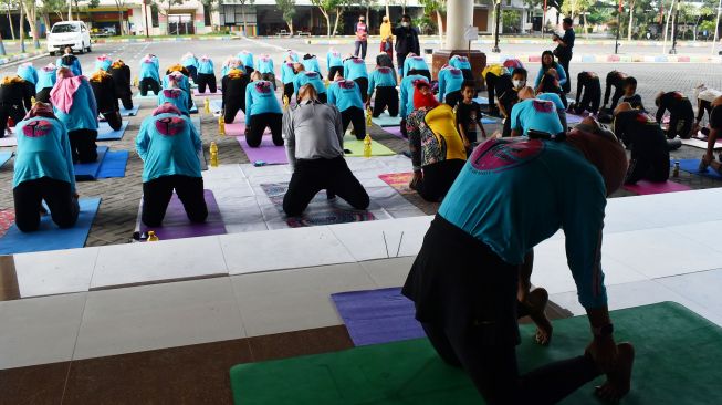 Anggota komunitas melakukan gerakan yoga saat mengikuti senam yoga bersama di luar ruangan di halaman GOR Wilis Kota Madiun, Jawa Timur, Minggu (10/4/2022).  ANTARA FOTO/Siswowidodo