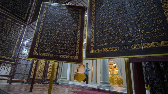 Pengunjung membaca ayat-ayat suci yang ada di Al Quran Al-Akbar di Palembang, Sumatera Selatan, Sabtu (9/4/2022).  ANTARA FOTO/Nova Wahyudi