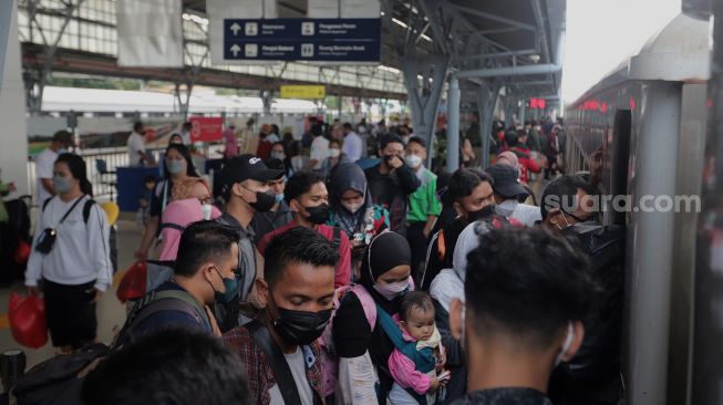 Sejumlah penumpang berjalan memasuki rangkaian kereta api Airlangga yang berhenti di Stasiun Pasar Senen, Jakarta, Minggu (10/4/2022). [Suara.com/Angga Budhiyanto]