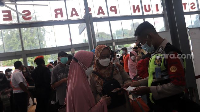 Petugas memeriksa kelengkapan dokumen calon penumpang kereta api di Stasiun Pasar Senen, Jakarta, Minggu (10/4/2022). [Suara.com/Angga Budhiyanto]