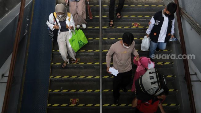 Sejumlah calon penumpang berjalan menuju rangkaian kereta api Airlangga yang berhenti di Stasiun Pasar Senen, Jakarta, Minggu (10/4/2022). [Suara.com/Angga Budhiyanto]