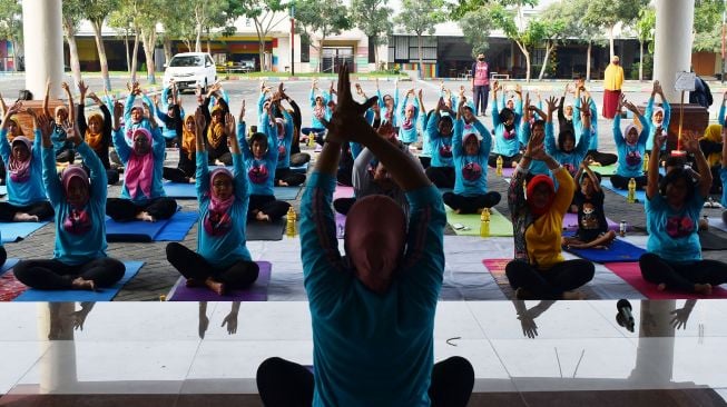 Anggota komunitas melakukan gerakan yoga saat mengikuti senam yoga bersama di luar ruangan di halaman GOR Wilis Kota Madiun, Jawa Timur, Minggu (10/4/2022).  ANTARA FOTO/Siswowidodo