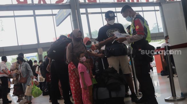 Petugas memeriksa kelengkapan dokumen calon penumpang kereta api di Stasiun Pasar Senen, Jakarta, Minggu (10/4/2022). [Suara.com/Angga Budhiyanto]