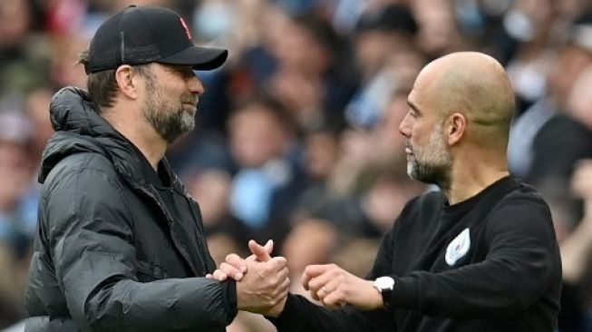 Manajer Liverpool Jerman Jurgen Klopp (kiri) berjabat tangan dengan manajer Manchester City Spanyol Pep Guardiola setelah pertandingan sepak bola Liga Inggris antara Manchester City dan Liverpool di Stadion Etihad di Manchester, Inggris, pada 10 April 2022. Pertandingan berakhir 2 -2. Paul ELLIS/AFP