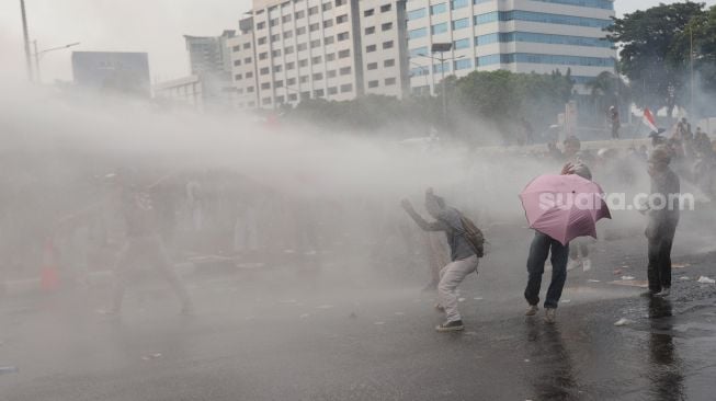 Polisi menembakkan 'water canon' kepada massa aksi saat unjuk rasa di depan gedung DPR RI, Jakarta, Senin (11/4/2022). [Suara.com/Angga Budhiyanto]