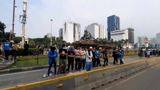 Mahasiswa peserta aksi 11 April melaksanakan salat Asar berjemaah di kawasan Patung Kuda, Jakpus. (Suara.com/Fakhri)