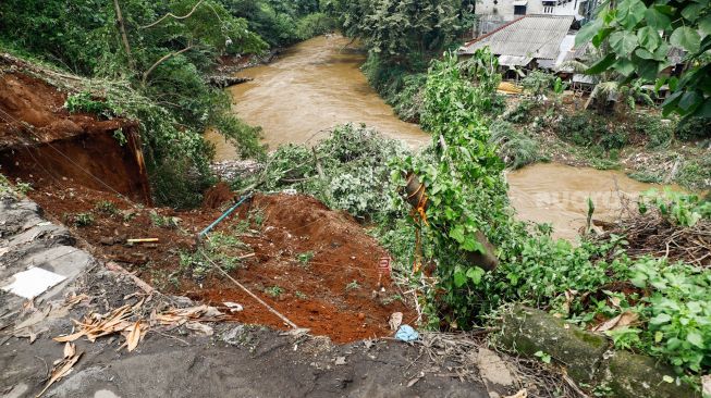 Warga melihat lokasi longsor didaerah bantaran sungai Ciliwung, Pengadegan Timur, Pancoran, Jakarta Selatan, Selasa (12/4/2022). [Suara.com/Alfian Winanto]