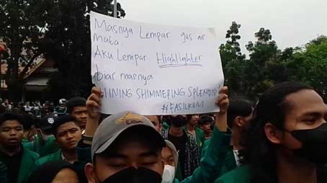 Mahasiswa yang tergabung dalam Aliansi Mahasiswa Riau membentangkan poster lucu bernada satire di depan Gedung DPRD Riau, Senin (11/4/2022). [Suara.com/Wahid Irawan]