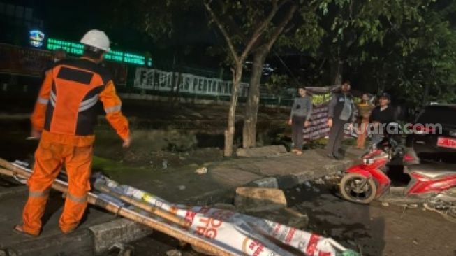 Petugas kebersihan memakai seragam orange membersihkan sampah dan batu yang berserakan di depan Kampus UMI Jalan Urip Sumoharjo Makassar, Selasa 12 April 2022 [SuaraSulsel.id/Istimewa]