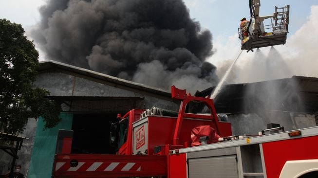 Petugas Dinas Pemadam Kebakaran Kota Surabaya memadamkan gudang yang terbakar di kawasan Pergudangan Margomulyo Permai, Surabaya, Jawa Timur, Selasa (12/4/2022).  ANTARA FOTO/Didik Suhartono
