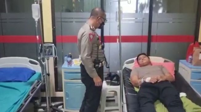 Dirlantas Polda Metro Jaya Kombes Sambodo Purnomo Yogo (kiri) menjenguk Polantas AKP Rudi Wira di RS Polri Kramat Jati, Jakarta Timur, Senin (11/4/2022), yang menjadi korban penganiayaan massa tidak dikenal saat berunjuk rasa di depan Gedung DPR/MPR RI. [Dok. Ditlantas Polda Metro Jaya]