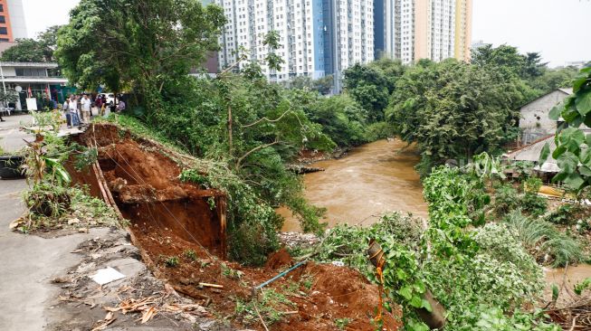 Warga melihat lokasi longsor didaerah bantaran sungai Ciliwung, Pengadegan Timur, Pancoran, Jakarta Selatan, Selasa (12/4/2022). [Suara.com/Alfian Winanto]