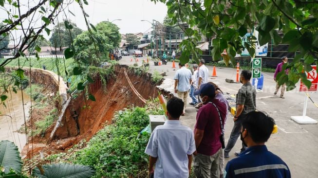 Warga melihat lokasi longsor didaerah bantaran sungai Ciliwung, Pengadegan Timur, Pancoran, Jakarta Selatan, Selasa (12/4/2022). [Suara.com/Alfian Winanto]