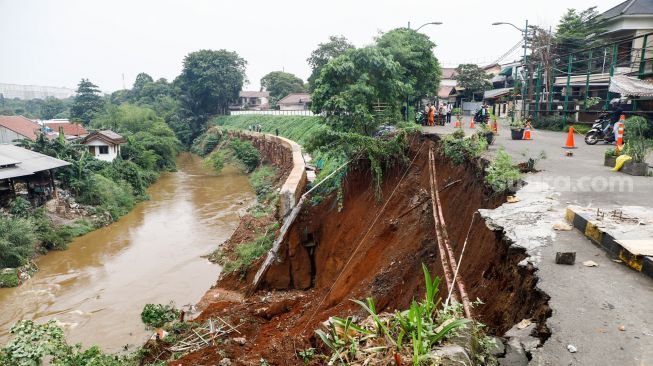 Warga melihat lokasi longsor didaerah bantaran sungai Ciliwung, Pengadegan Timur, Pancoran, Jakarta Selatan, Selasa (12/4/2022). [Suara.com/Alfian Winanto]