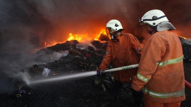 Petugas Dinas Pemadam Kebakaran Kota Surabaya memadamkan gudang yang terbakar di kawasan Pergudangan Margomulyo Permai, Surabaya, Jawa Timur, Selasa (12/4/2022).  ANTARA FOTO/Didik Suhartono
