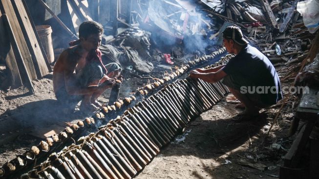 Pekerja menyelesaikan pembuatan lemang bambu di Kramat Raya, Senen, Jakarta Pusat, Rabu (13/4/2022). [Suara.com/Alfian Winanto]