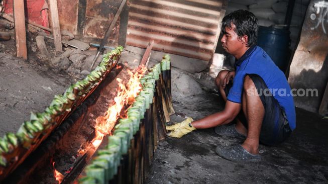 Pekerja menyelesaikan pembuatan lemang bambu di Kramat Raya, Senen, Jakarta Pusat, Rabu (13/4/2022). [Suara.com/Alfian Winanto]