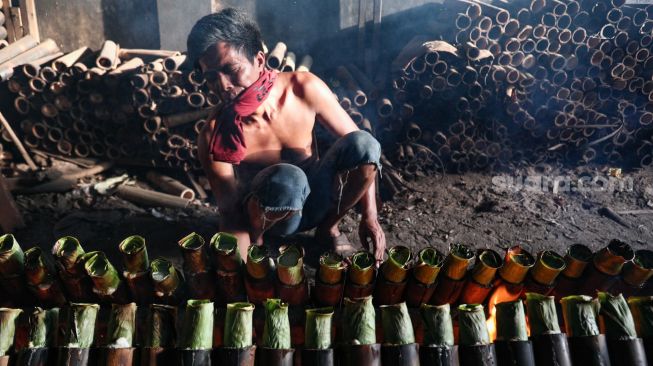 Pekerja menyelesaikan pembuatan lemang bambu di Kramat Raya, Senen, Jakarta Pusat, Rabu (13/4/2022). [Suara.com/Alfian Winanto]