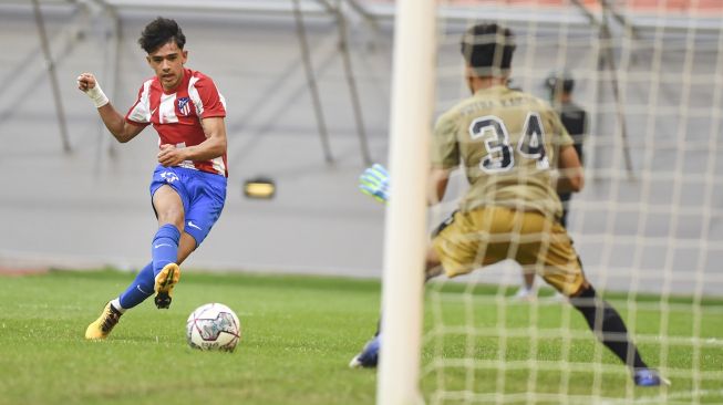 Pesepak bola Atletico Madrid U-18 Iker Luque Sierra (kiri) menendang bola yang menghasilkan gol ke gawang yang dijaga kiper bola Bali United U-18 I Made Putra Kaicen (kiri) pada pertandingan International Youth Championship (IYC) 2021 di Jakarta International Stadium. Jakarta, Rabu (13/4/2022).  ANTARA FOTO/Hafidz Mubarak