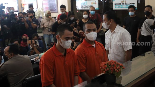 Tersangka pengeroyokan yang juga pengusaha pemilik gerai penjualan gawai, Putra Siregar (tengah) bersama artis Rico Valentino (kiri) dihadirkan saat rilis kasus di Polres Metro Jakarta Selatan, Rabu (13/4/2022). [Suara.com/Angga Budhiyanto]