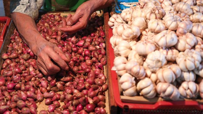 Pedagang memilah bawang yang akan dijual di Pasar PSPT Tebet, Jakarta Selatan, Kamis (14/4/2022). [Suara.com/Alfian Winanto]