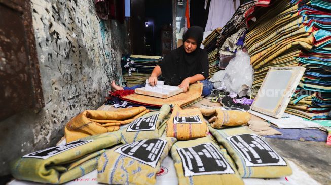 Pengrajin menyablon nama pada sajadah di Kawasan Kebon Melati, Tanah Abang, Jakarta Pusat, Kamis (14/4/2022). [Suara.com/Alfian Winanto]