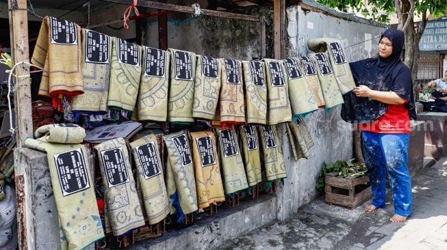 Pengrajin menjemur sajadah yang sudah di sablon di Kawasan Kebon Melati, Tanah Abang, Jakarta Pusat, Kamis (14/4/2022). [Suara.com/Alfian Winanto]