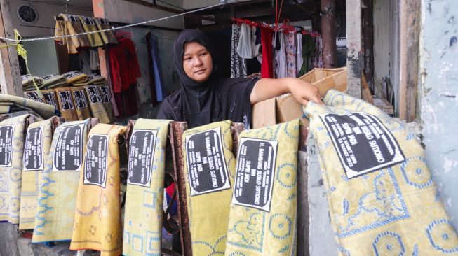 Pengrajin menjemur sajadah yang sudah di sablon di Kawasan Kebon Melati, Tanah Abang, Jakarta Pusat, Kamis (14/4/2022). [Suara.com/Alfian Winanto]