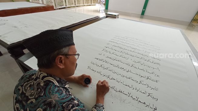 Proses penulisan Al-Quran Akbar yang dilakukan secara manual oleh Hayatuddin di Masjid Baitul Quran lantai 4, Kabupaten Wonosobo. [Suara.com / Citra Ningsih]
