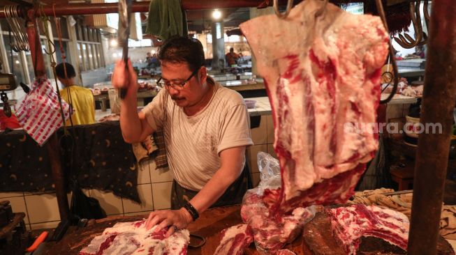 Pedagang memotong daging sapi di Pasar PSPT Tebet, Jakarta Selatan, Kamis (14/4/2022). [Suara.com/Alfian Winanto]