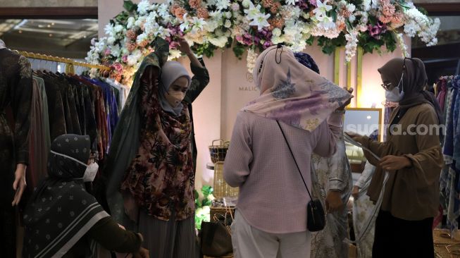 Pengunjung memilih busana muslim di area bazaar pakaian saat gelaran Indonesia Fashion Week 2022, Jakarta Convention Center (JCC), Jakarta, Jumat (15/4/2022). [Suara.com/Angga Budhiyanto]