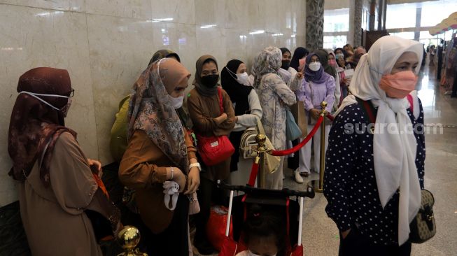 Pengunjung mengantre untuk mendapatkan busana muslim di area bazaar pakaian saat gelaran Indonesia Fashion Week 2022, Jakarta Convention Center (JCC), Jakarta, Jumat (15/4/2022). [Suara.com/Angga Budhiyanto]