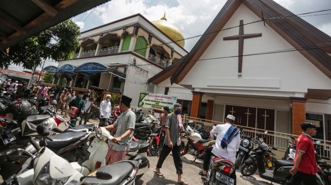 Warga berjalan di kawasan Gereja Nazaret (kanan) dan Masjid Al Azhar (kiri) di Jalan Gemini, Palangka Raya, Kalimantan Tengah, Jumat (15/4/2022).  ANTARA FOTO/Makna Zaezar
