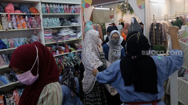 Pengunjung memilih busana muslim di area bazaar pakaian saat gelaran Indonesia Fashion Week 2022, Jakarta Convention Center (JCC), Jakarta, Jumat (15/4/2022). [Suara.com/Angga Budhiyanto]