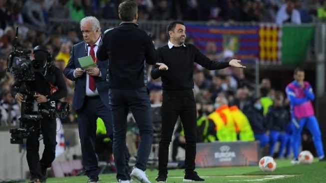 Gestur pelatih Barcelona Xavi Hernandez saat menyaksikan kekalahan timnya dari Eintracht Frankfurt di leg kedua babak perempat final Liga Europa yang digelar di Camp Nou, Jumat (15/4/2022). [AFP]