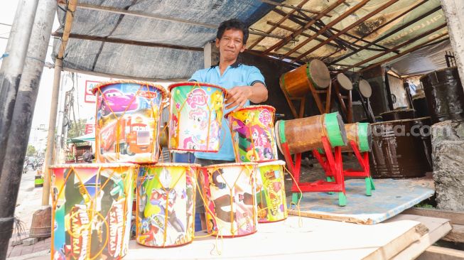 Penjual menyusun bedug dagangannya di Jalan KH Mas Mansyur, Tanah Abang, Jakarta Pusat, Jumat (15/4/2022). [Suara.com/Alfian Winanto]