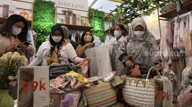 Pengunjung memilih busana muslim di area bazaar pakaian saat gelaran Indonesia Fashion Week 2022, Jakarta Convention Center (JCC), Jakarta, Jumat (15/4/2022). [Suara.com/Angga Budhiyanto]