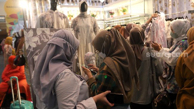 Pengunjung memilih busana muslim di area bazaar pakaian saat gelaran Indonesia Fashion Week 2022, Jakarta Convention Center (JCC), Jakarta, Jumat (15/4/2022). [Suara.com/Angga Budhiyanto]