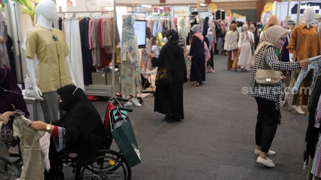 Pengunjung memilih busana muslim di area bazaar pakaian saat gelaran Indonesia Fashion Week 2022, Jakarta Convention Center (JCC), Jakarta, Jumat (15/4/2022). [Suara.com/Angga Budhiyanto]