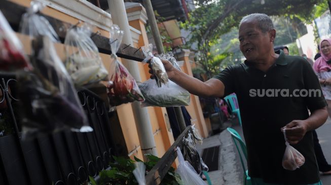 Warga memilah sayuran yang dijajakan secara gratis di Jalan Jati Padang VI RT 002 RW 004, Pasar Minggu, Jakarta, Minggu (17/4/2022). [Suara.com/Angga Budhiyanto]