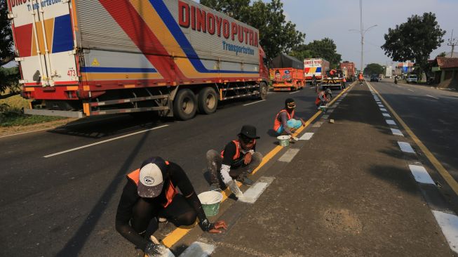 Sejumlah pekerja menyelesaikan pengecatan marka jalan di jalur pantura Widasari, Indramayu, Jawa Barat, Sabtu (16/4/2022). [ANTARA FOTO/Dedhez Anggara/wsj]