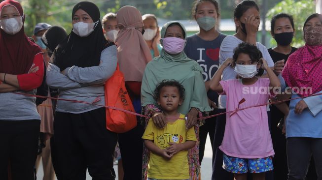 Sejumlah warga mengantre untuk mendapatkan sayuran dan pakaian bekas layak pakai yang dijajakan secara gratis di Jalan Jati Padang VI RT 002 RW 004, Pasar Minggu, Jakarta, Minggu (17/4/2022). [Suara.com/Angga Budhiyanto]