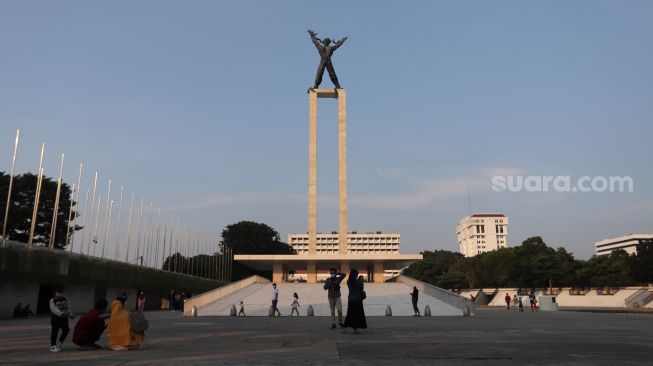 Warga berfoto di Lapangan Banteng, Jakarta, Minggu (17/4/2022). [Suara.com/Angga Budhiyanto]