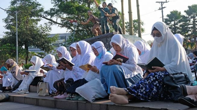 Sejumlah warga tadarus Al Quran bersama saat memperingati Nuzulul Quran di kawasan taman Pancasila kota Temanggung, Jawa Tengah, Minggu (17/4/2022).  ANTARA FOTO/Anis Efizudin
