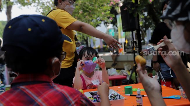 Peserta mengikuti lomba melukis telur di Lapangan Banteng, Jakarta, Minggu (17/4/2022). [Suara.com/Angga Budhiyanto]