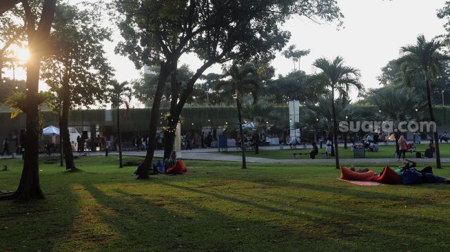 Warga bersantai di Lapangan Banteng, Jakarta, Minggu (17/4/2022). [Suara.com/Angga Budhiyanto]