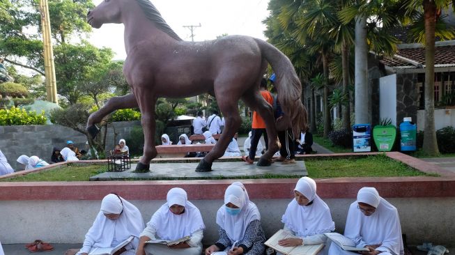 Sejumlah warga tadarus Al Quran bersama saat memperingati Nuzulul Quran di kawasan taman Pancasila kota Temanggung, Jawa Tengah, Minggu (17/4/2022).  ANTARA FOTO/Anis Efizudin
