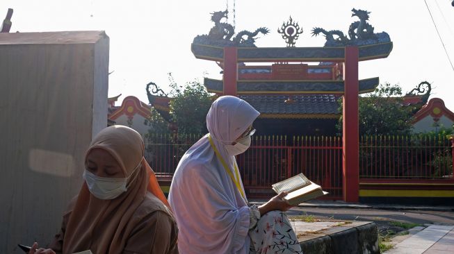 Warga tadarus Al Quran saat memperingati Nuzulul Quran di depan Klenteng kong Ling Bio kawasan taman Pancasila kota Temanggung, Jawa Tengah, Minggu (17/4/2022). ANTARA FOTO/Anis Efizudin