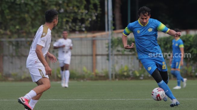 Pemain Selebritis FC Darius Sinathrya berusaha melewati lawan saat mengikuti sesi latihan di Lapangan ABC, Kompleks Gelora Bung Karno, Jakarta, Senin (18/4/2022). [Suara.com/Angga Budhiyanto]