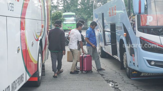 Calon pemudik mengantri untuk menaiki bus di Terminal Kampung Rambutan, Jakarta Timur, Senin (18/4/2022). [Suara.com/Alfian Winanto]